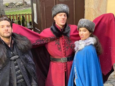 Sujaya Dasgupta, Simon Sears, and Ben Barnes are wearing a blue gown, red gown, and a black gown respectively. 